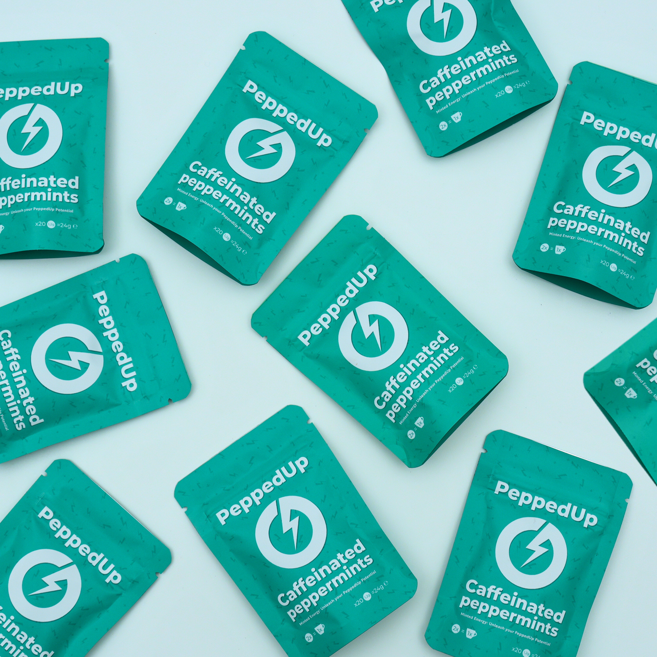 Multiple teal PeppedUp pouches arranged randomly on flat pastel background